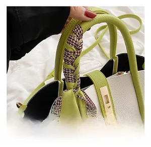 Detail of lychee pattern leather handbag with green handle and houndstooth scarf wrap