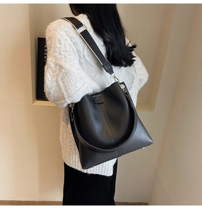 Detail view of large black bucket bag with wide black and white woven shoulder strap