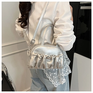 Detail of silver pleated bowling bag with adjustable shoulder strap on a model