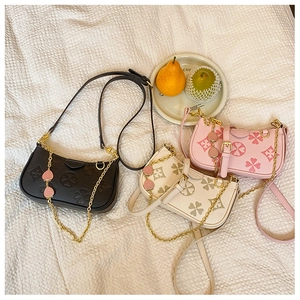 Detailed view of three embossed clover crossbody bags in black, cream, and pink colors