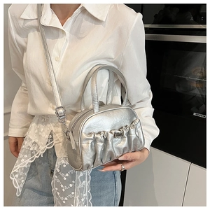 Detail view of silver pleated shell bag with metallic finish and adjustable strap
