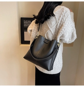 Detail of matte black leather bucket bag featuring vertical stitching and metal buckle
