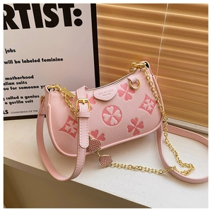 Detail of pink clover embossed leather bag with gold chain strap and strawberry charm
