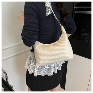 Close-up of beige hobo bag with wavy texture and adjustable shoulder strap on model