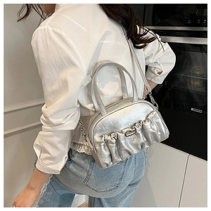 Detail of silver metallic pleated handbag with a sleek metal clasp shown as a crossbody bag