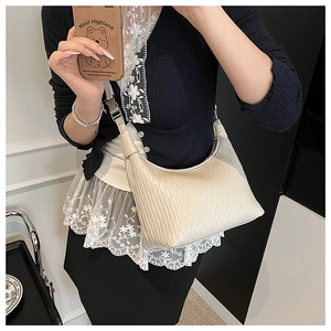 Close-up of pleated off-white crescent bag with wavy texture and silver metal hardware