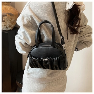 Detail of black pleated bowling bag showing metal swivel lock and soft leather texture