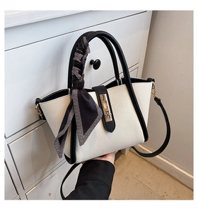 Close-up of black and white trapezoid tote bag with gold metal lock and silk scarf detail