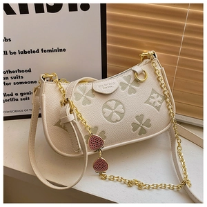 Detail of lychee textured leather bag with clover pattern and red strawberry charm