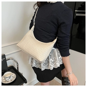 Detail of cream-colored hobo bag with wavy pleated texture and adjustable shoulder strap