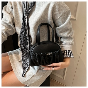 Detail of a black pleated crossbody bag with premium silver clasp and textured PU leather