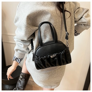 Detail of black pleated PU leather handbag with silver heart buckle and adjustable strap