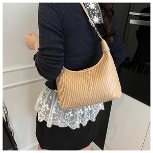 Detail of ruched apricot shoulder bag with lace ribbon strap on a model
