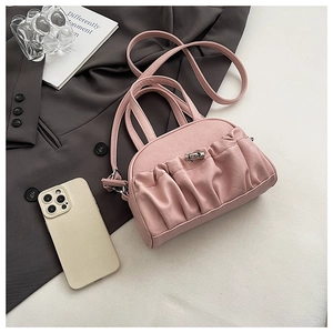 Detailed close-up of pink pleated handbag with silver twist lock on soft fabric base