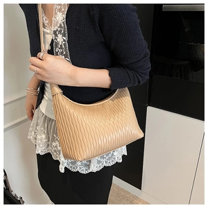 Detail of beige pleated shoulder bag featuring elegant embossed wave texture and satin finish