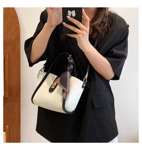 Detail of black and white contrast handbag with gold twist lock and blue floral scarf