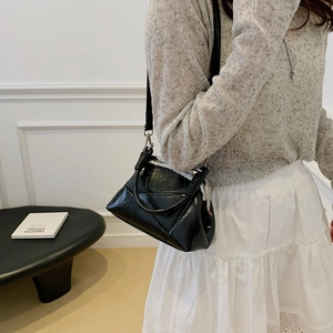 Model wearing black crocodile pattern bag with round handle in a minimalist interior setting