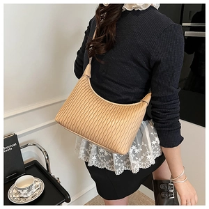 Close-up of beige hobo bag featuring vertical pleated texture and premium leather strap