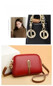 Macro detail of litchi texture leather shell bag with metal T logo pendant in red and black