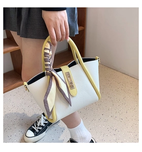 Detail of white lychee textured tote bag with yellow handles and a decorative silk scarf