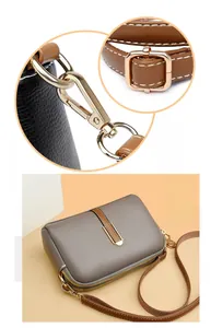 Detail of detachable adjustable shoulder strap with golden metal hardware on grey bag