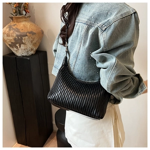 Matelassé black leather shoulder bag styled with denim jacket in artistic interior setting