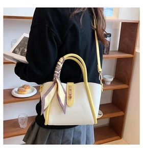Detailed shot of contrast color leather handbag with silk scarf on handle and shoulder strap