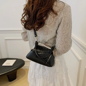 Detail of vintage black glossy crossbody bag with white lace trim and metal clasp