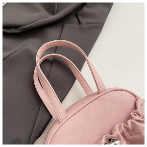 Close-up of pink pleated leather handbag featuring twin handles and silver metal hardware