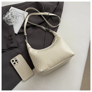 Detail of cream pleated hobo bag featuring vertical wavy texture and silver metal buckle