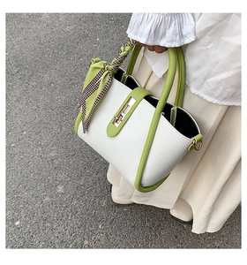 Detail of contrast color tote bag with lychee texture, metal lock and silk scarf handle
