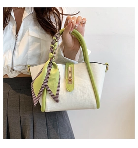 Detail of white lychee leather handbag with green handle and decorative silk scarf