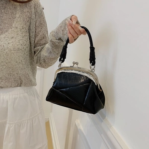 Detail of vintage black frame bag with white lace trim and metallic top handle