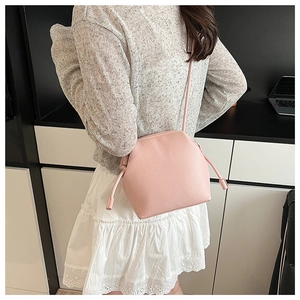 Pink lychee grain leather bucket bag shown from a side-back view on a model indoors