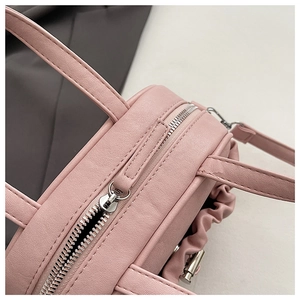 Close-up of pink lychee grain faux leather handbag with silver zipper and pleated details