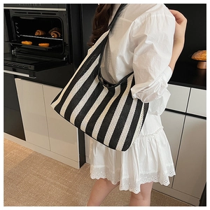 Black and white striped knit tote bag shown in a stylish kitchen setting on a shoulder