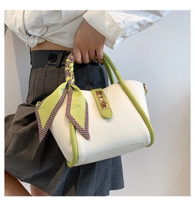 Detail of vintage white and green leather handbag with decorative silk scarf on handle