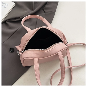 Detail view of pink pleated handbag interior with zipper opening and shoulder strap
