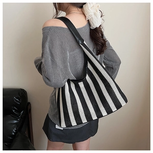 Detail of nautical striped knit tote bag with black leather shoulder strap and side label