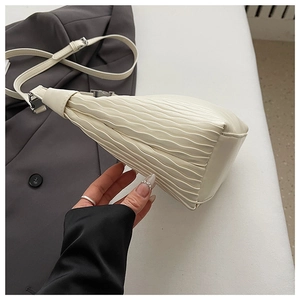 Detail shot of beige shoulder bag showing vertical wavy pleats and silver hardware