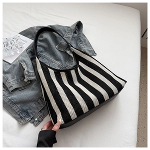 Close-up of nautical striped tote bag with leather base on a flat lay aesthetic background