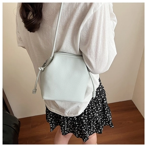Detailed view of mint green crossbody bucket bag with textured lychee grain leather