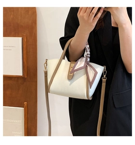 Close-up of white lychee leather handbag with decorative scarf and brown strap