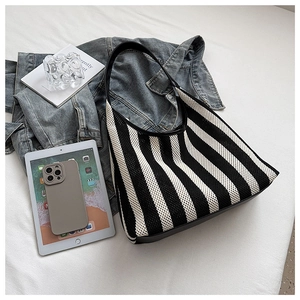 Detailed knit texture of black and white striped hobo bag with black leather strap