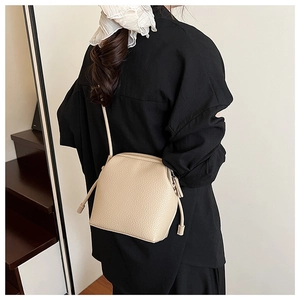 Close-up of beige lychee texture leather shell bag shown on model for size and fit