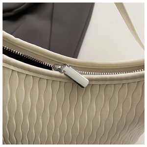Detail of wavy pleated texture and silver zipper on a cream white shoulder bag