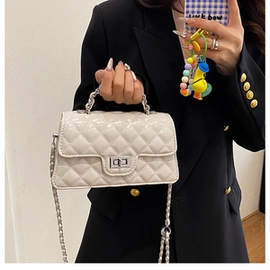 Close-up of a white quilted patent leather crossbody bag with silver chain and metal clasp