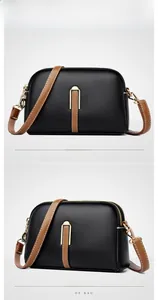 Detail of black lychee leather crossbody bag with brown strap and golden U-shaped hardware