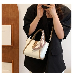 Detail of cream crossbody bag with litchi texture, metal clasp and plaid silk scarf