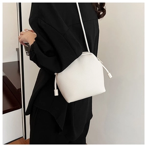 Close-up of a white lychee grain leather crossbody bag with minimalist knot details